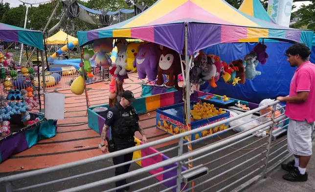 A police officer responds after a shooting at Seattle Center during the Bite of Seattle food festival Sunday, July 26, 2026, in Seattle, Wash. (AP Photo/Lindsey Wasson)