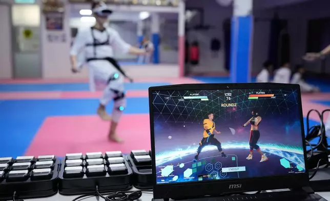 A laptop displays a virtual taekwondo match as a practitioner trains in Puchong, on the outskirts of Kuala Lumpur, Malaysia, Thursday, April 23, 2026. (AP Photo/Vincent Thian)