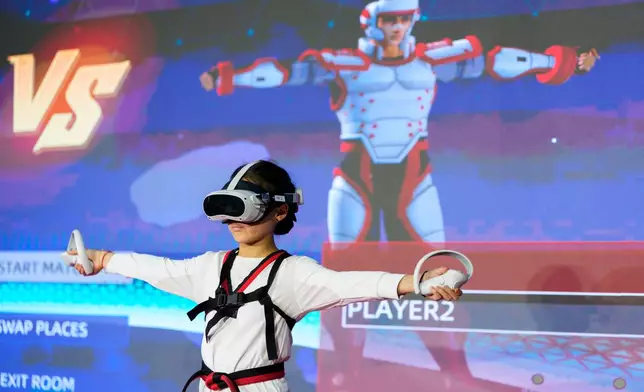 Victoria Siow, 12, calibrates motion-tracking sensors and virtual reality controllers during a virtual taekwondo competition event in Kuala Lumpur, Malaysia, Saturday, June 20, 2026. (AP Photo/Vincent Thian)