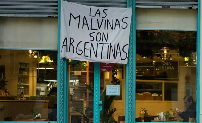 A man sits at a restaurant displaying a banner reading "The Malvinas are Argentine," referring to the Falkland Islands, also known as Malvinas, in Buenos Aires, Argentina, Monday, July 27, 2026. (AP Photo/Natacha Pisarenko)