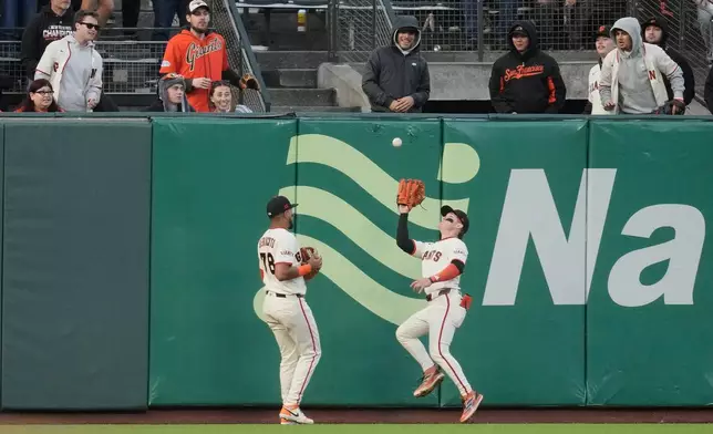 San Francisco Giants left fielder Victor Bericoto, left, watches as center fielder Drew Gilbert, right, catches a fly out hit by Colorado Rockies' Kyle Karros during the fifth inning of a baseball game Thursday, July 9, 2026, in San Francisco. (AP Photo/Jeff Chiu)
