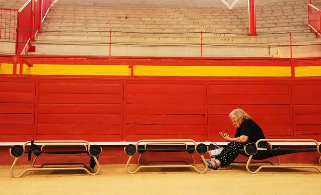 A resident sits at a bullring serving as a temporary shelter after being evacuated from their homes because of the threat of a wildfire in Valdemorillo, Madrid province, Spain, Saturday, July 25, 2026. (AP Photo/Manu Fernandez)