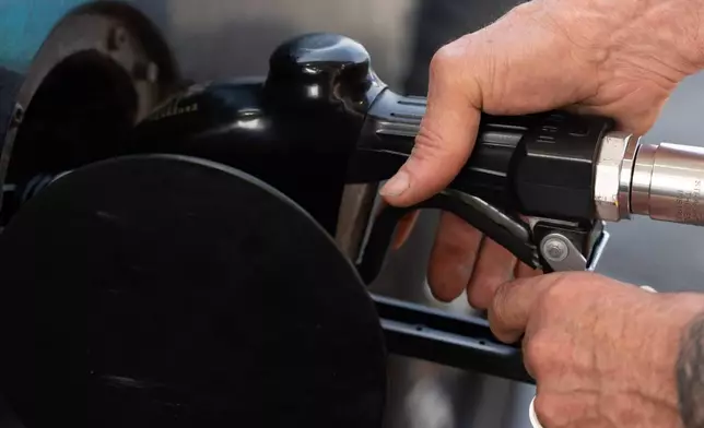 FILE - A person secures the fuel nozzel while filling up their tank at a gas station on Tuesday, May 12, 2026, in Portland, Ore. (AP Photo/Jenny Kane, File)