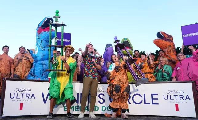 Chase Mertz, of Seattle, and "Tiny Rex," Mimi Miyazawa, of Orem, Utah, celebrate with their men's and women's championship trophies after competing in the T-Rex World Championship Races at Emerald Downs, Sunday, July 12, 2026, in Auburn, Wash. (AP Photo/Lindsey Wasson)