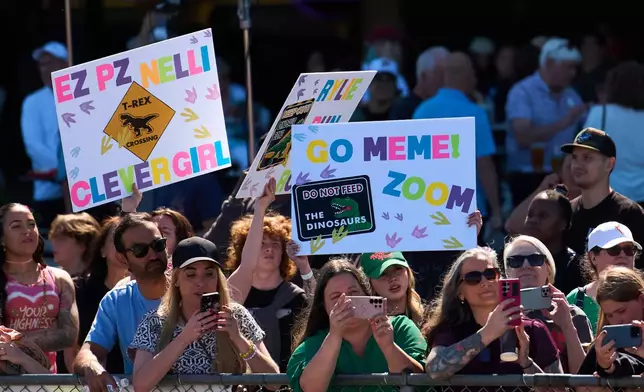People wave signs for their favorite racers during the T-Rex World Championship Races at Emerald Downs, Sunday, July 12, 2026, in Auburn, Wash. (AP Photo/Lindsey Wasson)
