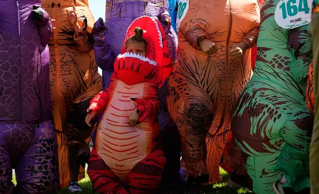 Tilly Sawangwan, 5, stands with other adult T. rex participants during the T-Rex World Championship Races at Emerald Downs, Sunday, July 12, 2026, in Auburn, Wash. (AP Photo/Lindsey Wasson)