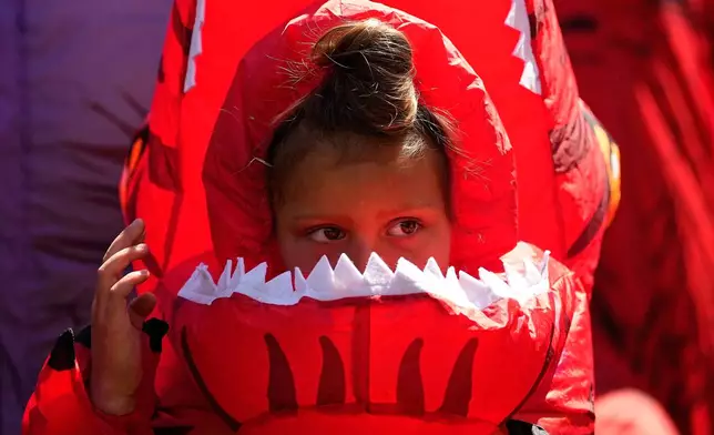 Tilly Sawangwan, 5, looks on in a red costume during the T-Rex World Championship Races at Emerald Downs, Sunday, July 12, 2026, in Auburn, Wash. (AP Photo/Lindsey Wasson)
