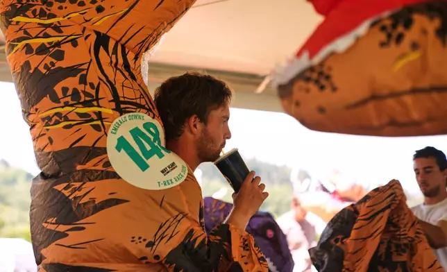 Jaymen Parker keeps hydrated before running in the T-Rex World Championship Races at Emerald Downs, Sunday, July 12, 2026, in Auburn, Wash. (AP Photo/Lindsey Wasson)