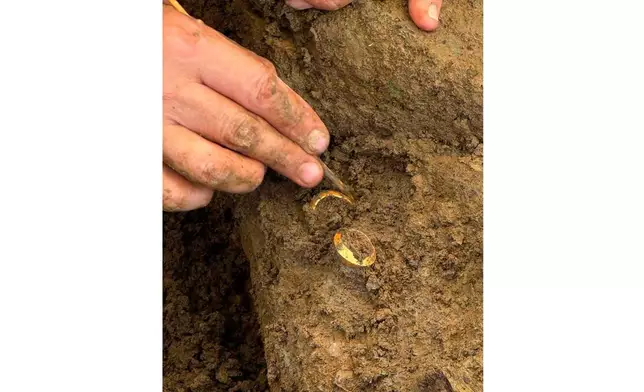 In this photo released by The Fine Arts Department, an archaeologist shows two rings with human bones during an ongoing dig at the Don Yai Thong archeological site in Phetchaburi province, Thailand Thursday, July 2, 2026. (The Fine Arts Department via AP)