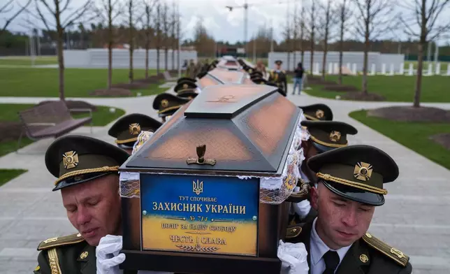FILE - An honor guard carries the coffins of unidentified Ukrainian soldiers killed in battle during the Russian-Ukrainian war at a funeral ceremony at a military cemetery near Kyiv, Ukraine, April 30, 2026. (AP Photo/Evgeniy Maloletka, File)
