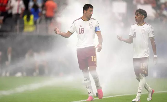 Spain's Rodri (16) and Lamine Yamal (19) chat as they walk among sprinklers during the World Cup semifinal soccer match between France and Spain in Arlington, Texas, near Dallas, Tuesday, July 14, 2026. (AP Photo/Eric Gay)