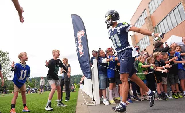 Seattle Seahawks wide receiver Jaxon Smith-Njigba greets young fans as he runs out during the NFL football team's training camp, Sunday, July 26, 2026, in Renton, Wash. (AP Photo/Lindsey Wasson)