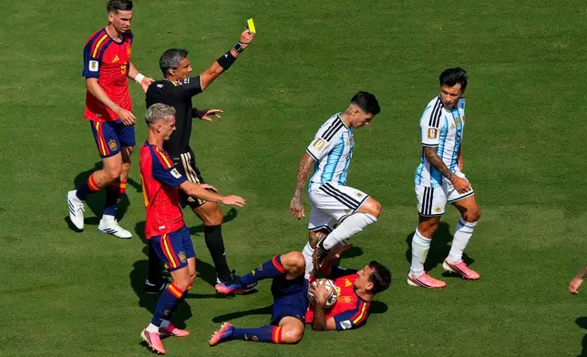 Argentina's Lisandro Martinez, right, receives a yellow card as Argentina's Enzo Fernandez steps over Spain's Mikel Oyarzabal, during the World Cup final soccer match between Spain and Argentina in East Rutherford, N.J., near New York, Sunday, July 19, 2026. (AP Photo/Yuki Iwamura)