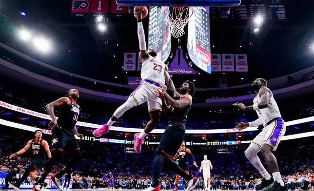 FILE - Los Angeles Lakers' LeBron James, center left, goes up for the shot against Philadelphia 76ers' Joel Embiid, center right, during the second half of an NBA basketball game, Dec. 7, 2025, in Philadelphia. (AP Photo/Chris Szagola, File)