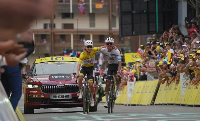 Slovenia's Tadej Pogacar, left, and Mexico's Isaac Del Toro, right, celebrate as they cross the finish line of the twentieth stage of the Tour de France cycling race with start in Le Bourg d'Oisans and finish in Alpe d'huez, France, Saturday, July 25, 2026. (AP Photo/Thibault Camus)
