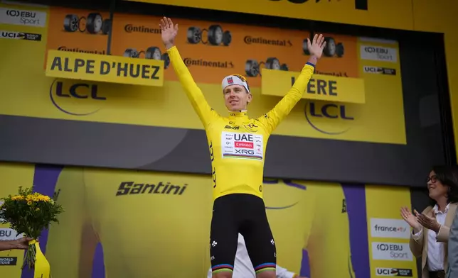 Slovenia's Tadej Pogacar, wearing the overall leader's yellow jersey, celebrates on the podium after the twentieth stage of the Tour de France cycling race with start in Le Bourg d'Oisans and finish in Alpe d'huez, France, Saturday, July 25, 2026. (AP Photo/Thibault Camus)