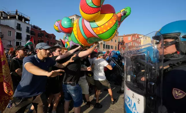 Police officers face demonstrators gathered to protest against U.S. Ambassador Tilman Fertitta's luxury yacht 'Boardwalk" presence in Venice, Friday, July 17, 2026. (AP Photo/Luca Bruno) CORRECTS NAME OF YACHT TO BOARDWALK INSTEAD OF BOARDWALL"