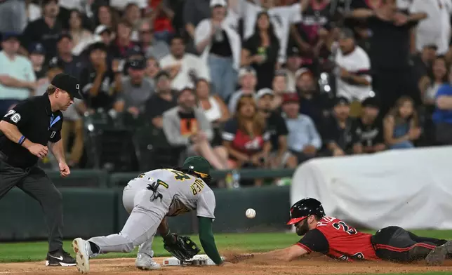 Chicago White Sox's Tristan Peters, right, slides safely into third base for an RBI triple while Athletics third baseman Joshua Kuroda-Grauer, center, catches the throw during the seventh inning of a baseball game in Chicago, Friday, July 10, 2026. (AP Photo/Paul Beaty)