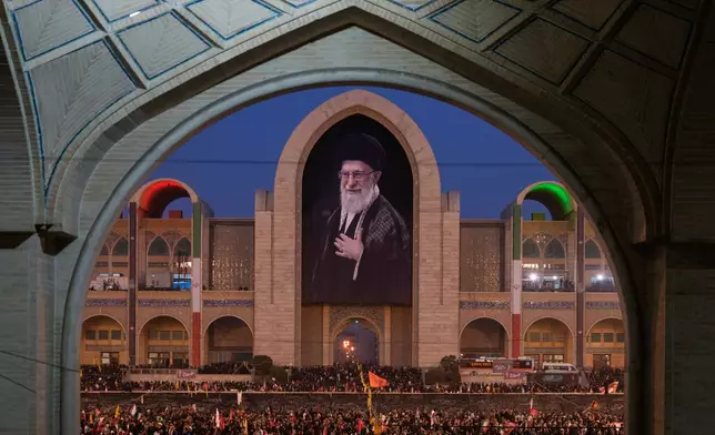 Mourners gather beneath a portrait of the late Iranian Supreme Leader Ayatollah Ali Khamenei during the funeral ceremonies for Khamenei and members of his family at the Imam Khomeini Mosalla Grand Mosque in Tehran, Iran, Saturday, July 4, 2026. (AP Photo/Altaf Qadri)