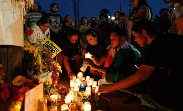 Attendees light candles during a vigil for Lorenzo Salgado Araujo, a Mexican national fatally shot by a federal immigration agent a day prior, Wednesday, July 8, 2026, in Houston. (AP Photo/Mark Felix)
