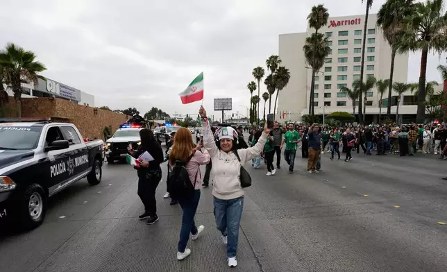 Fans wave flags as the Iran World Cup soccer team leaves their hotel for the airport Tuesday, June 30, 2026, in Tijuana, Mexico. (AP Photo/Gregory Bull)