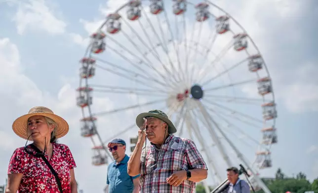 Visitors react to the heat while attending the Great American State Fair on the National Mall, Wednesday, July 1, 2026, in Washington. (AP Photo/Nathan Howard)