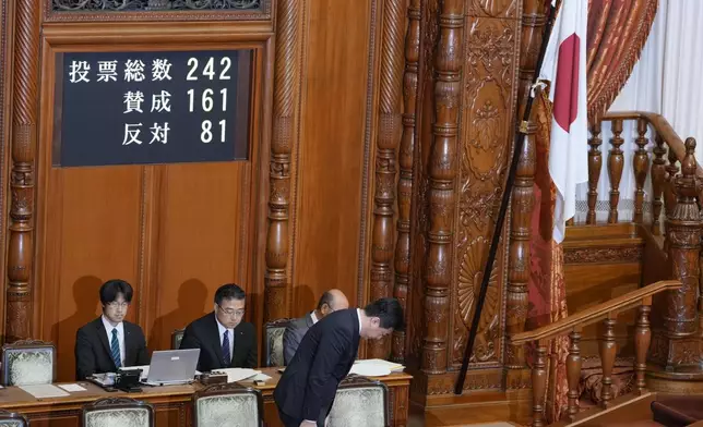 Japan's Chief Cabinet Secretary Minoru Kihara stands and bows to members of the House of Councillors beside a Japanese national flag after lawmakers passed a law prohibiting desecration of its national flag, during a parliamentary plenary session in Tokyo, Friday, July 17, 2026. (AP Photo/Eugene Hoshiko)