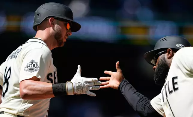 Seattle Mariners' Mitch Garver greets first base coach Eric Young Jr. after hitting a two-run home run against the Toronto Blue Jays during the fourth inning of a baseball game, Sunday, July 5, 2026, in Seattle. (AP Photo/Lindsey Wasson)