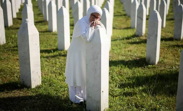 A Bosnian Muslim woman mourns next to the grave of her relative, victim of the Srebrenica genocide, in the Srebrenica Memorial Centre in Potocari, Bosnia, Saturday, July 11, 2026. (AP Photo/Armin Durgut)