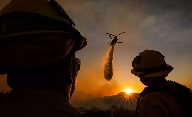 Firefighters watch as a helicopter drops water on the Summit Fire in Llano, CA. Friday, July 10, 2026. (AP Photo/Ethan Swope)