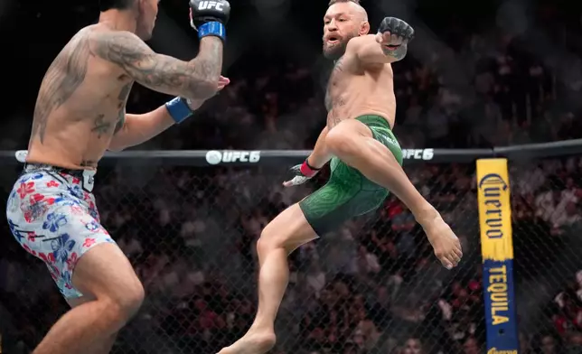 Conor McGregor, right, jumps into the air for a kick as he fights Max Holloway in a welterweight fight at the UFC 329 mixed martial arts event Saturday, July 11, 2026, in Las Vegas. (AP Photo/John Locher)