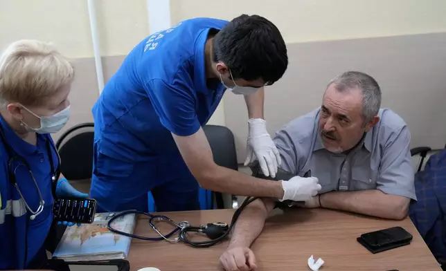 Emergency medical personnel provide care to Russian politician Boris Nadezhdin, right, accused of displaying "extremist symbols," during a break at a courtroom in the town of Dolgoprudny, outside Moscow, Russia, Friday, July 17, 2026. (AP Photo/Pavel Bednyakov)