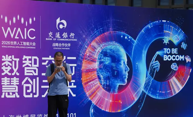 A visitor stands near a poster for the World AI Conference in Shanghai, China on July 17, 2026. (AP Photo/Ng Han Guan)