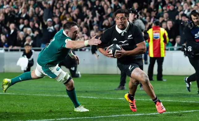 New Zealand's Anton Lienert-Brown, right, breaks a tackle from Ireland to score a try during their Nations Championship rugby international test match in Auckland, New Zealand, Saturday, July 18, 2026. (Brett Phibbs/Photosport via AP)