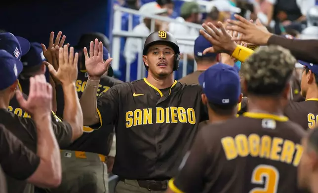 San Diego Padres' Manny Machado, center, is congratulated by teammates after scoring on a two-run single by Ty France against the Miami Marlins during the third inning of a baseball game, Saturday, July 25, 2026, in Miami. (AP Photo/David Santiago)