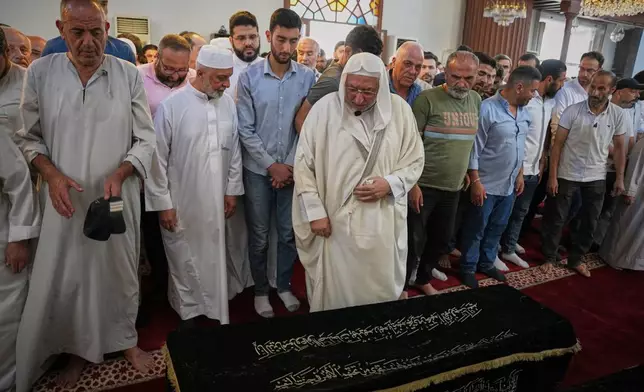 Mourners pray over the coffin of Fathi Muhammad Saeed Qabbani, who was killed Tuesday when an explosive device detonated in a cafe near Damascus' main courthouse complex, during his funeral in the Al-Midan neighborhood of Damascus, Syria, Friday, July 3, 2026. (AP Photo/Omar Albam)