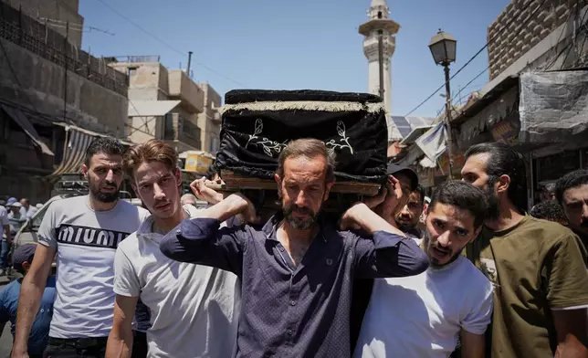 Mourners carry the coffin of Fathi Muhammad Saeed Qabbani, who was killed Tuesday when an explosive device detonated in a cafe near Damascus' main courthouse complex, during his funeral in the Al-Midan neighborhood of Damascus, Syria, Friday, July 3, 2026. (AP Photo/Omar Albam)