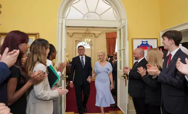 Staff clap as new Prime Minister Andy Burnham and wife Marie-France van Heel walk into 10 Downing Street in London, Monday, July 20, 2026. (AP Photo/Kin Cheung, Pool)