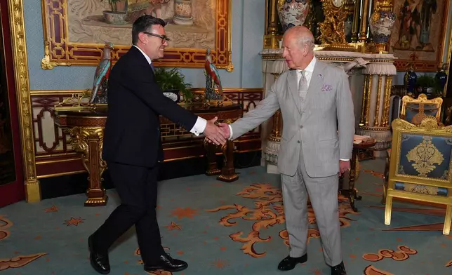 Britain's King Charles III welcomes Andy Burnham, left, during an audience at Buckingham Palace, London, where he invited the leader of the Labour Party to become Prime Minister and form a new government, Monday July 20, 2026. (Aaron Chown/Pool Photo via AP)