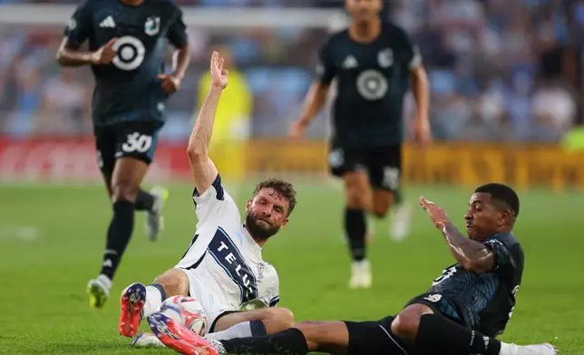 Vancouver Whitecaps FC midfield Thomas Müller (13) slides into Minnesota United FC defense Morris Duggan (23) during the first half of an MLS soccer match on Saturday, July 25, 2026, in St. Paul, Minn. (AP Photo/Adam Bettcher)