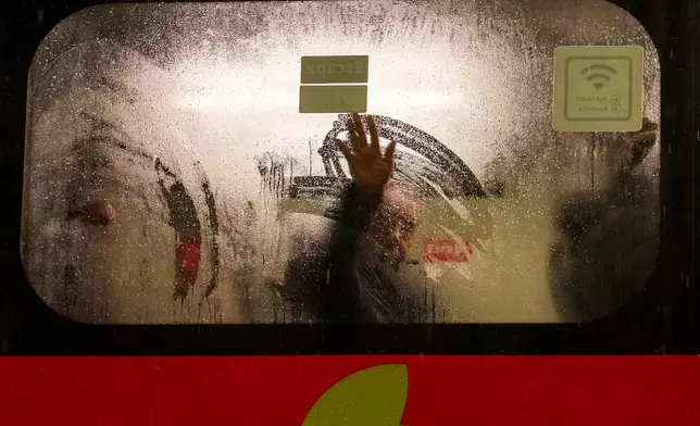 A man on a bus wipes frost from the window during a rainstorm in Santiago, Chile, early Monday, July 20, 2026. (AP Photo/Esteban Felix)