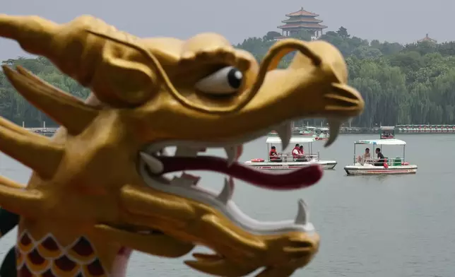 Visitors ride boats on a lake against the Jingshan Pavilion as they visit Beihai Park, one of the oldest and best preserved ancient imperial gardens in Beijing Thursday, July 23, 2026. (AP Photo/Andy Wong)
