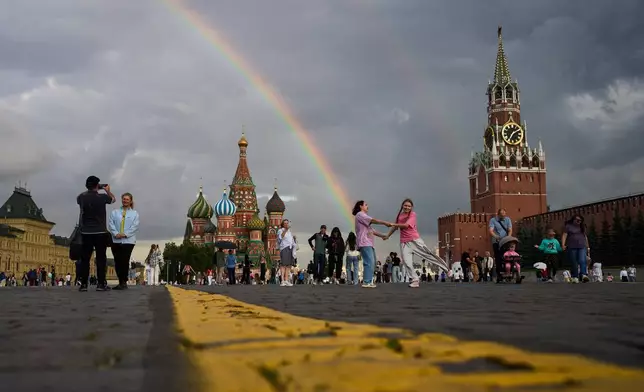 People enjoy a golden hour and rainbow as they walk in Red Square in Moscow, Thursday, July 23, 2026, backdropped by the St. Basil's Cathedral, center, and the Spasskaya Tower, right. (AP Photo/Alexander Zemlianichenko)