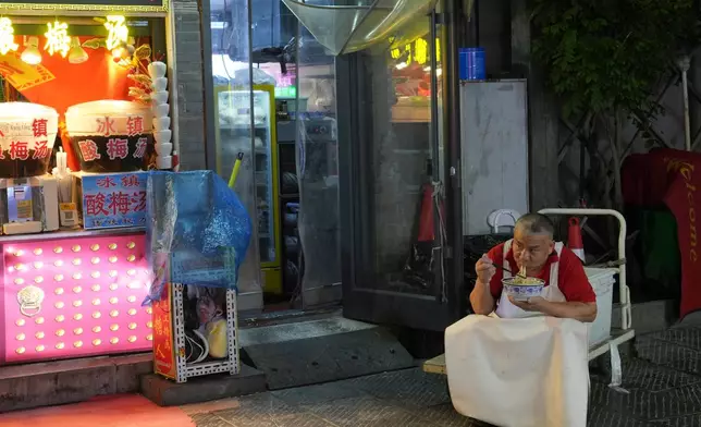 A man eats noodles on Qianmen Street in Beijing, China, on Wednesday, July 22, 2026. (AP Photo/Achmad Ibrahim)