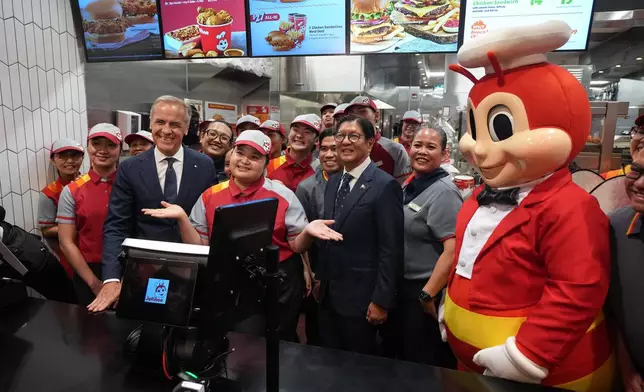 Canada's Prime Minister Mark Carney, left, and Philippines President Ferdinand Marcos Jr., right, pose with employees during a visit to a Jollibee fast food restaurant, in Vancouver, Thursday, July 2, 2026. (Darryl Dyck/The Canadian Press via AP)