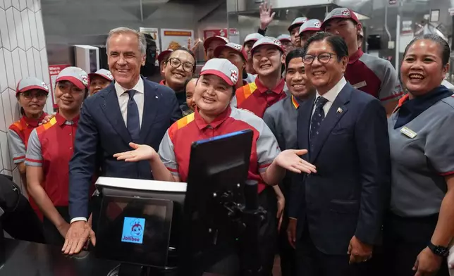 Canada's Prime Minister Mark Carney, left, and Philippines President Ferdinand Marcos Jr., right, pose with employees during a visit to a Jollibee fast food restaurant, in Vancouver, Thursday, July 2, 2026. (Darryl Dyck/The Canadian Press via AP)
