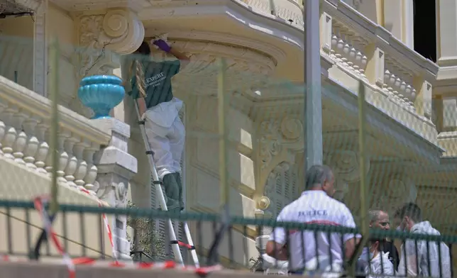 An investigator examines the scene at the residential building where an explosive device seriously injured three people a day earlier in Monaco, Tuesday, June 30, 2026. (AP Photo/Philippe Magoni)