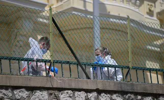 Investigators examine the scene at the residential building where an explosive device seriously injured three people a day earlier in Monaco, Tuesday, June 30, 2026. (AP Photo/Philippe Magoni)