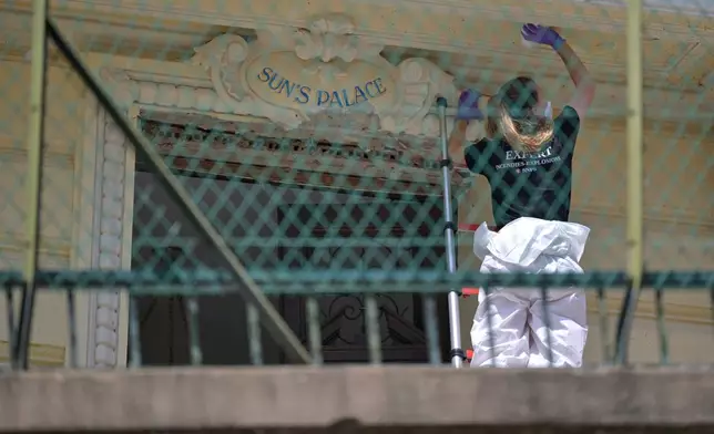 An investigator examines the scene at the residential building where an explosive device seriously injured three people a day before, in Monaco, Tuesday, June 30, 2026. (AP Photo/Philippe Magoni)