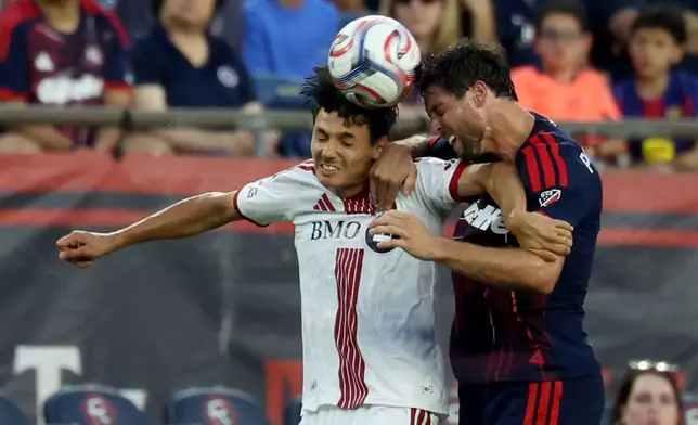 Toronto FC's Dániel Sallói, left, and New England Revolution's Matt Polster, right, head the ball in the first half of an MLS soccer match, Wednesday, July 22, 2026, in Foxborough, Mass. (AP Photo/Mark Stockwell)